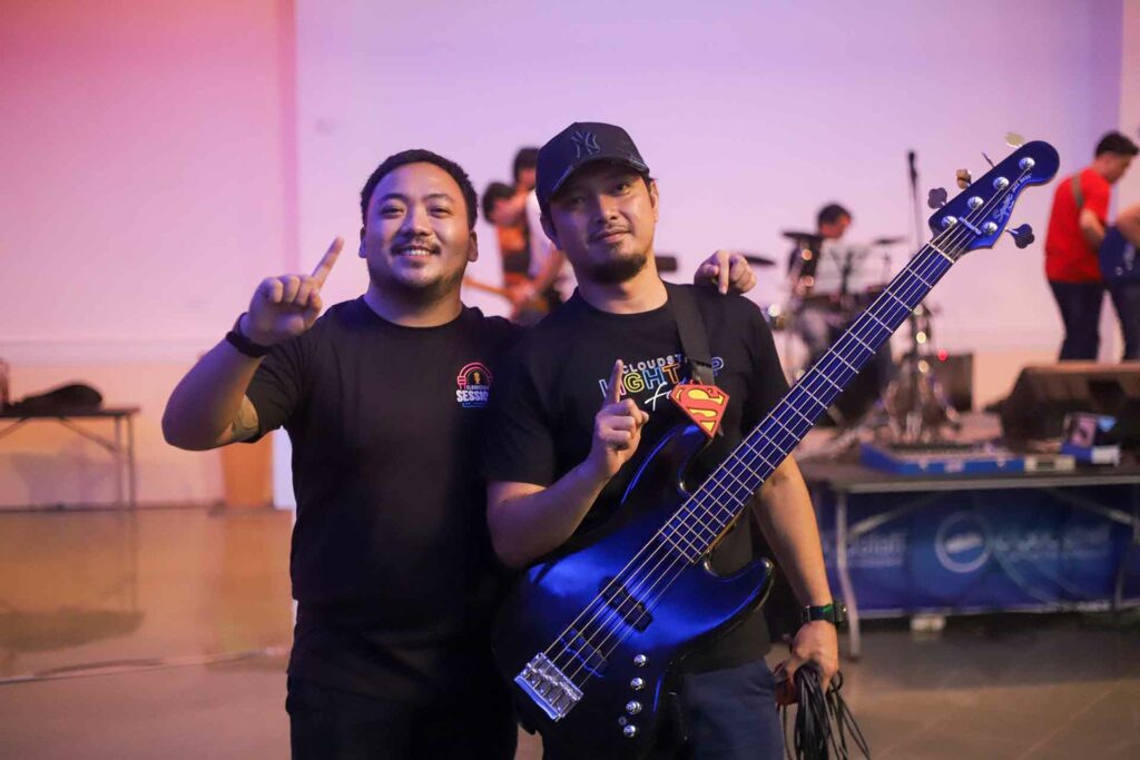 Two male Cloudstaffers, one with a guitar, doing the #1 sign